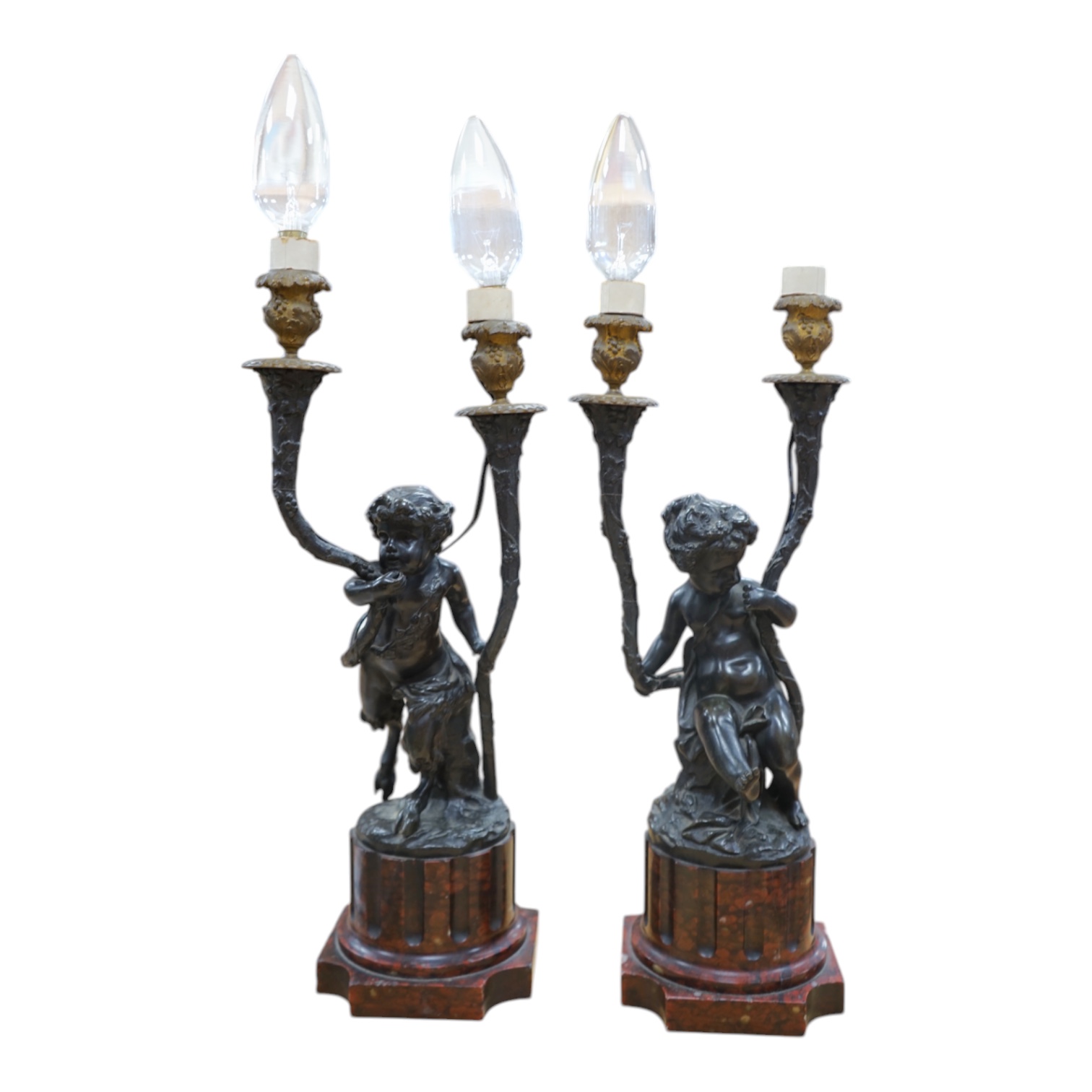 A pair of French bronze cupid twin candelabra with leaf shaped twin arms upon rouge marble fluted columns, after Clodion c.1840, 44cm high, excluding the fitting. Condition - fair